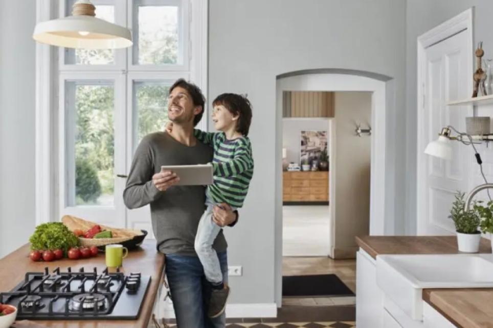 Father and son in kitchen looking up a pendant light